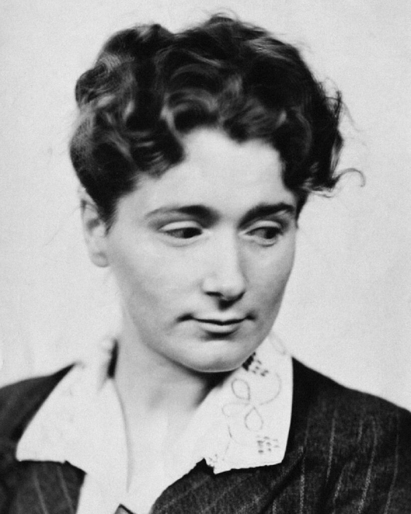 Author Helene Bessette, pictured in black and white wearing a white collar under a dark jacket and looking toward the bottom corner.